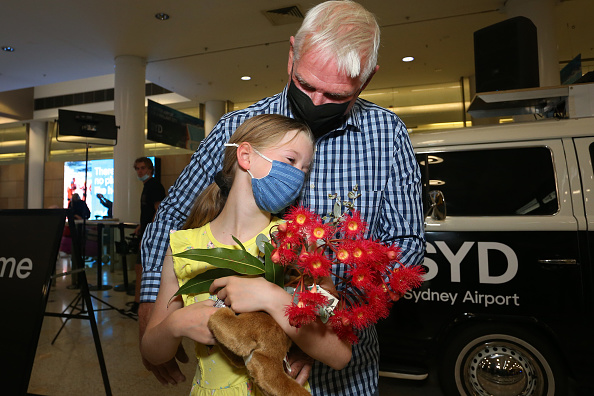 SYDNEY, AUSTRALIA - FEBRUARY 21: Charlotte Roempke greets her grandfather Bernie Edmonds as he arrives at Sydney's International Airport on February 21, 2022 in Sydney, Australia. Australia is welcoming fully-vaccinated international travellers for the first time since closing its borders to all non-citizens and non-residents in March 2020 to limit the spread of COVID-19. (Photo by Lisa Maree Williams/Getty Images)