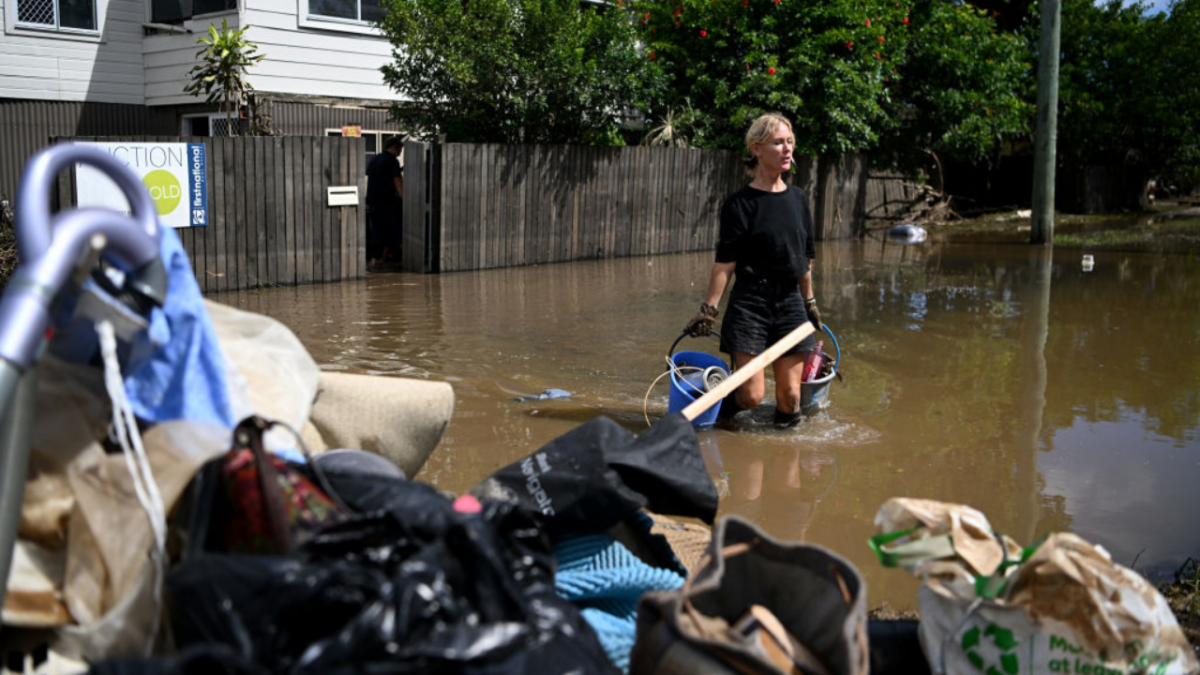 A woman stands in flood waters in Woodburn, northern rivers.