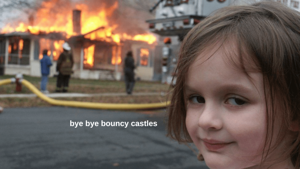Disaster girl meme of child smiling at camera in foreground of burning building with 'bye bye bouncy castles' text overlaid