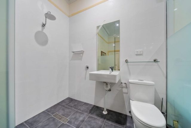 A tiled bathroom with a shower, sink, mirror and toilet