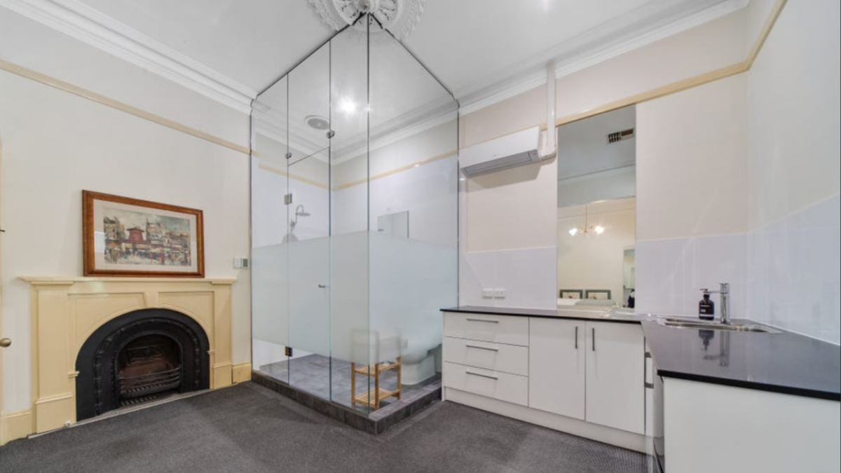 A rental property with a glass cube bathroom next to the kitchen and a fireplace.