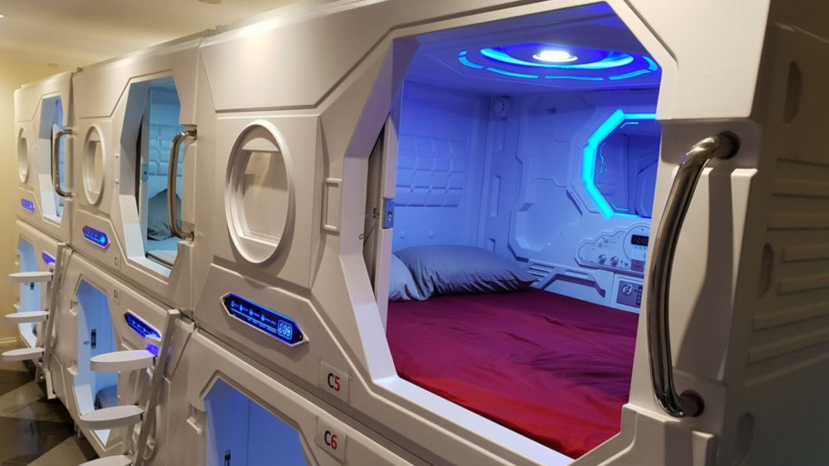 sleeping pod interior with a red bedspread and fluorescent, blue lighting