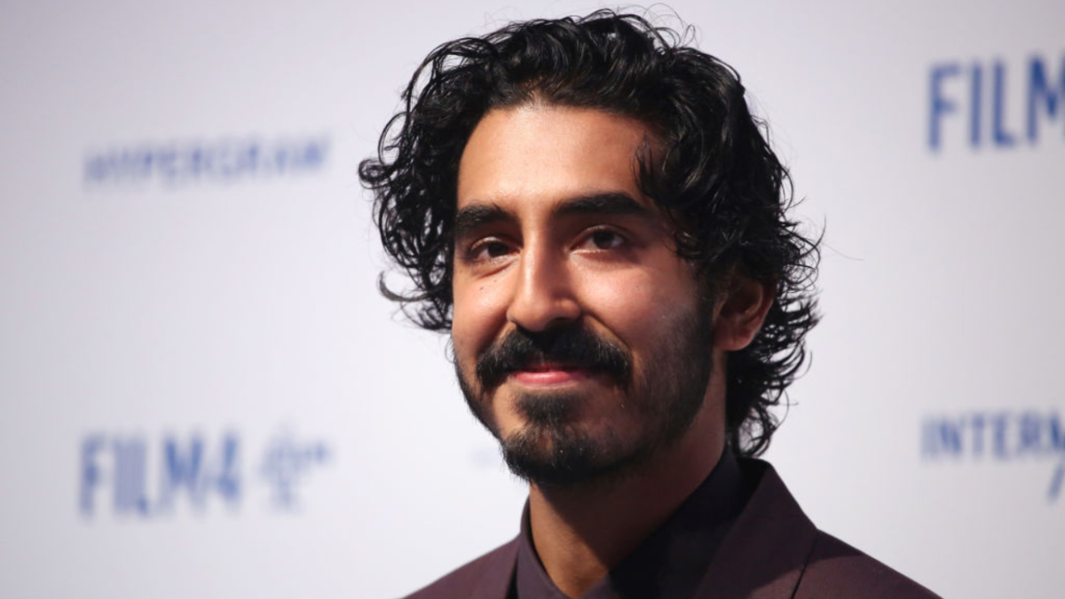 Actor Dev Patel in a burgundy suit at a film premiere