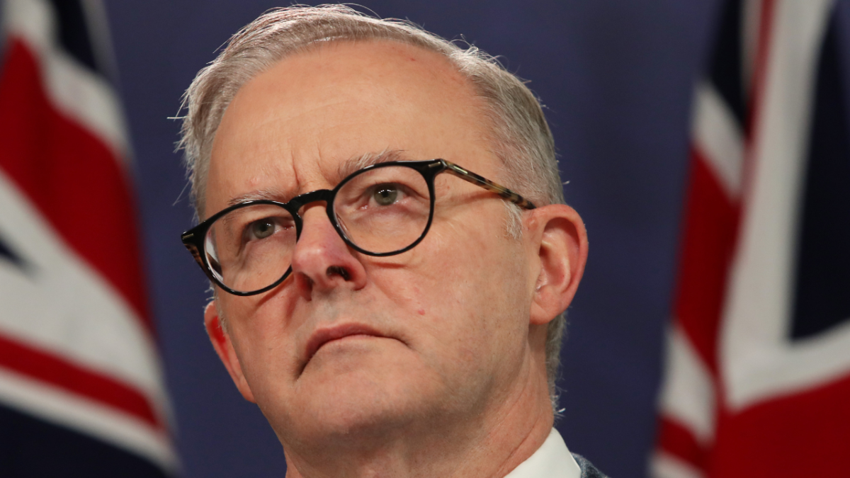 Australian Prime Minister Anthony Albanese speaking at a press conference with Australian flag in background