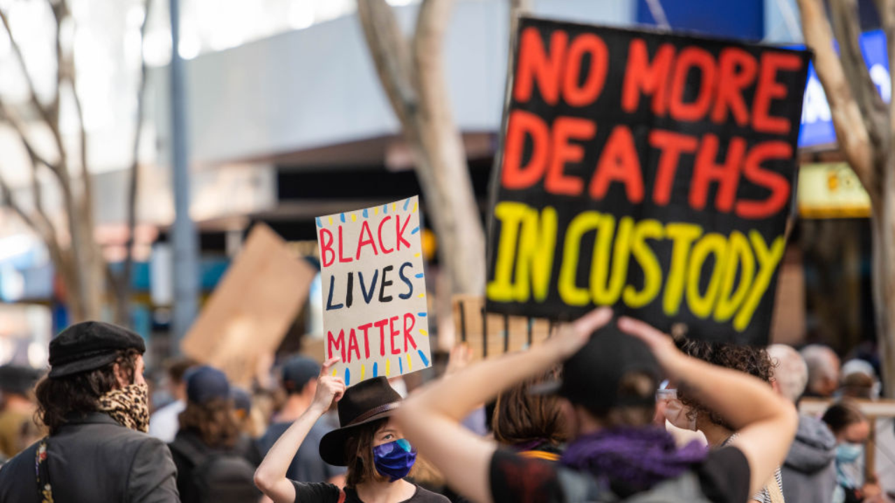Protester hold a 'Black Lives Matter' and 'No more deaths in custody' placards during a protest in Brisbane.
