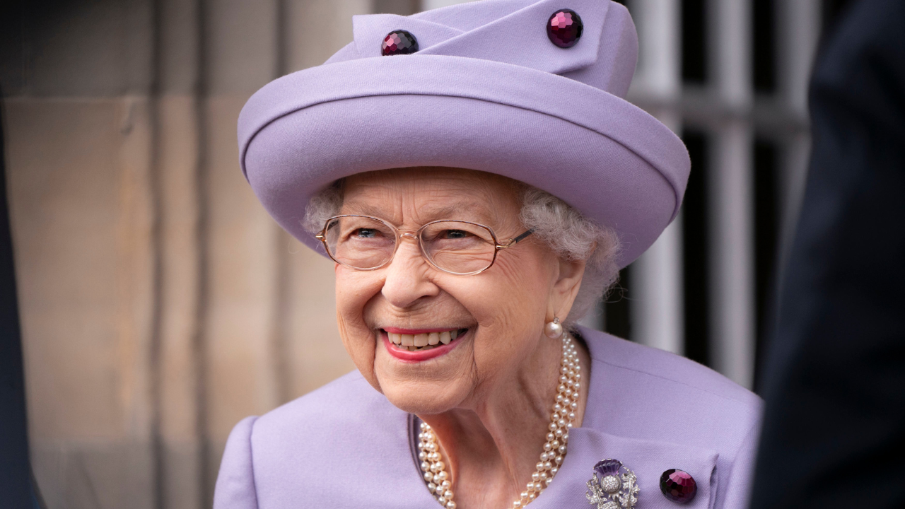 Queen Elizabeth II attends an Armed Forces Act of Loyalty Parade at the Palace of Holyroodhouse in a purple hat and jacket