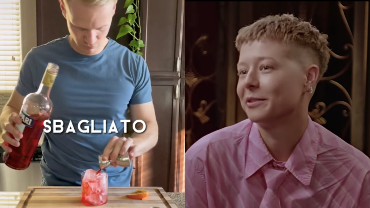 Bartender in blue t-shirt pouring Campari into a glass to make a negroni sbagliato and actor Emma D'Arcy wearing a pink shirt and tie leaning in, smiling