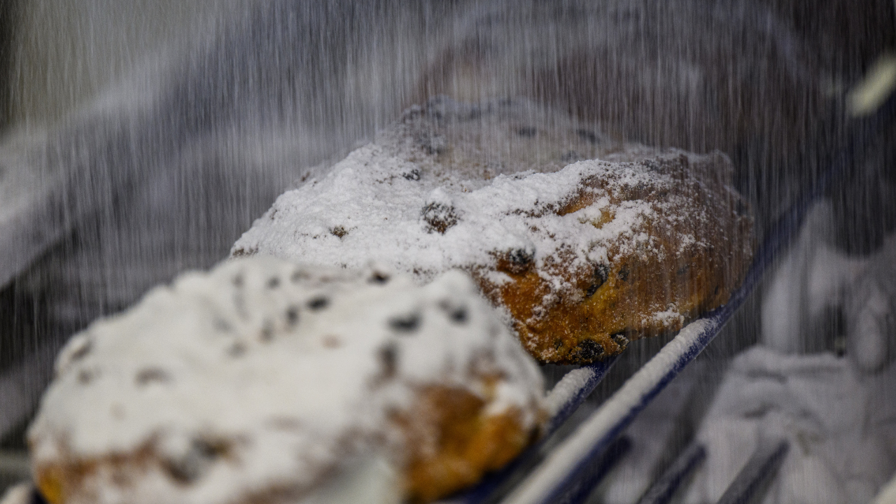 Baked Dresden Christmas stollen is sprinkled with powdered sugar at a bakery