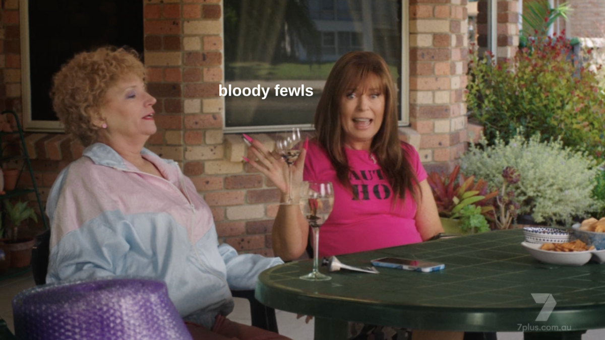 Kath and Kim sharing a wine outside in Kath & Kim: Our Effluent Life with Kim saying "bloody fewls"