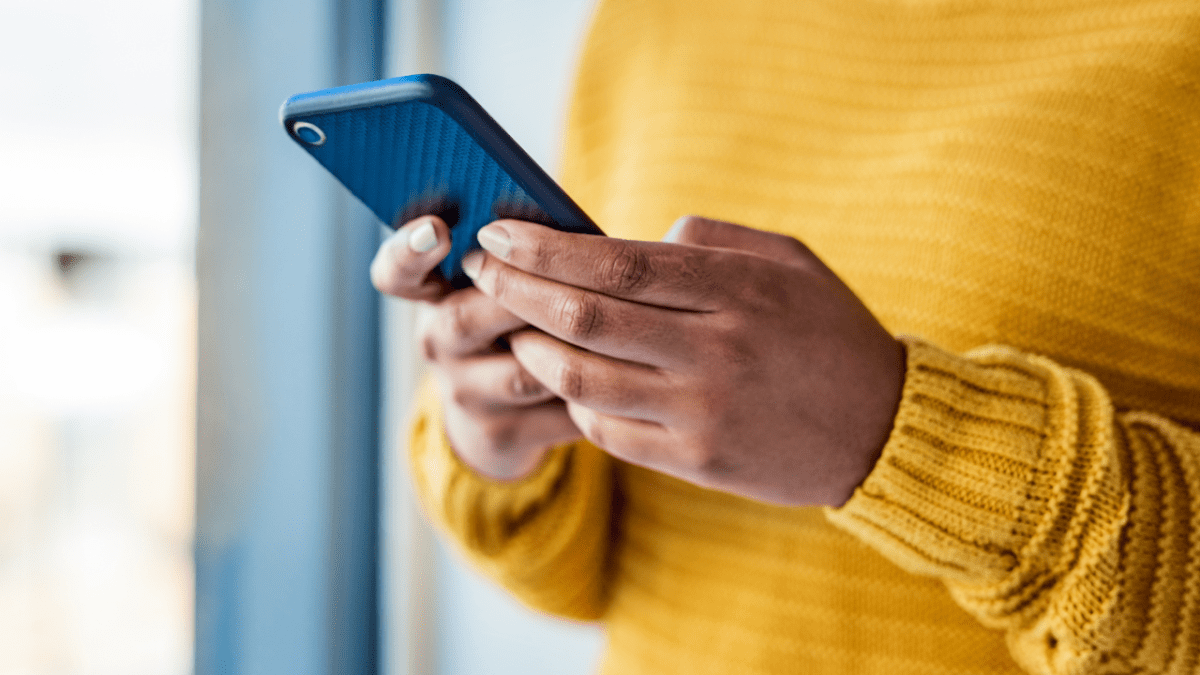 Woman wearing a yellow jumper using her phone