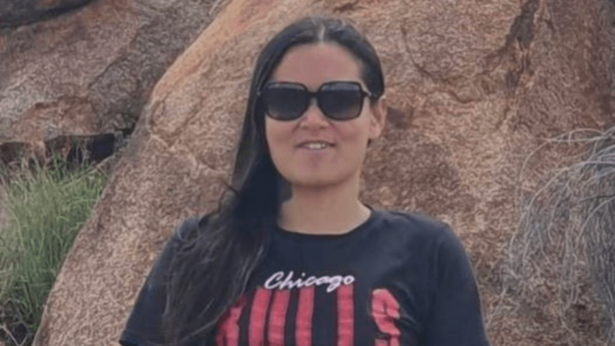 Missing Northern Territory woman Angie Fuller wearing black glasses and a black t-shirt with red and white text on it.
