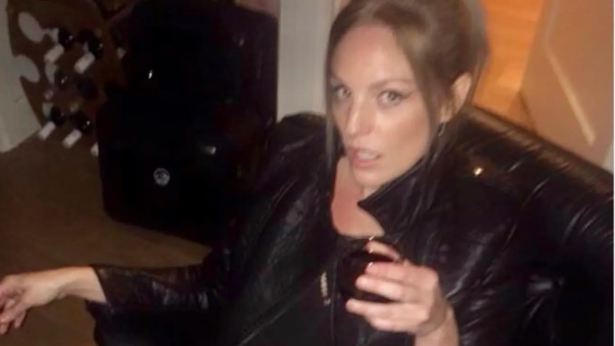 Melbourne woman Heide Bos, who described herself as a dominatrix, sitting on couch in black leather jacket holding glass