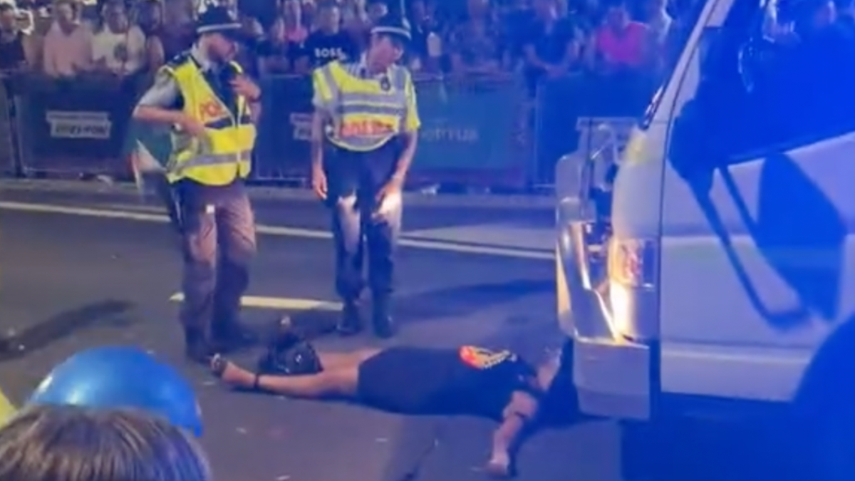 Two NSW Police officers standing over Lidia Thorpe as she lays in front of a police float at Sydney Mardi Gras 2023
