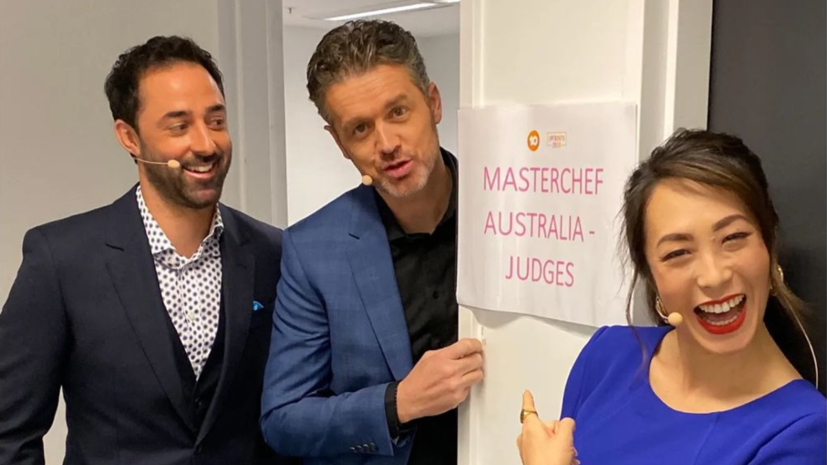 Andy Allen, Jock Zonfrillo and Melissa Leong smiling in front of sign which reads "MasterChef Australia - judges"