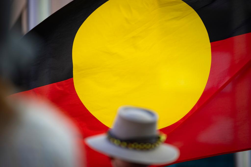 An Aboriginal flag is seen through the crowd at the "Stop Black Deaths In Custody" march on October 7, 2023 in Boorloo.