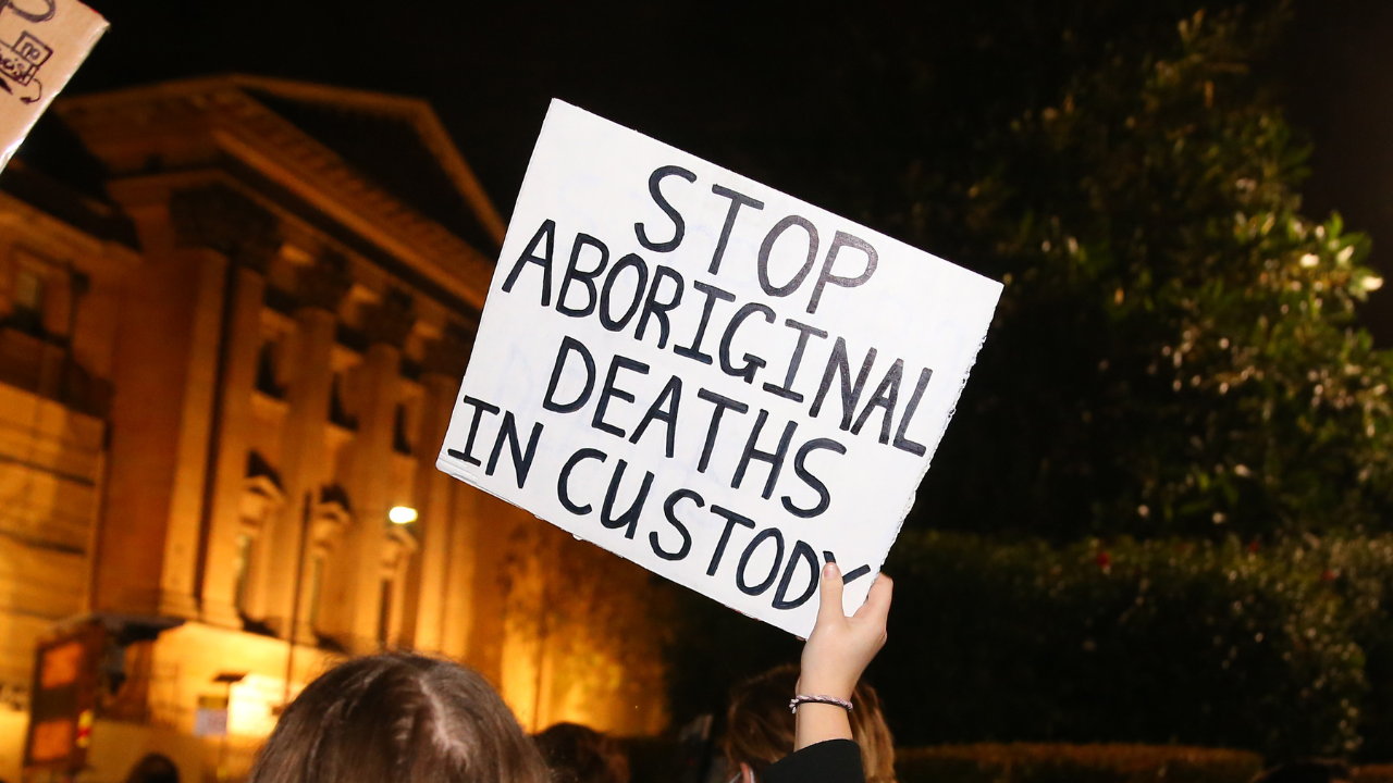 Victoria Has Decriminalised Public Drunkenness — Here's How Its New Response Works Instead. Image is of a "stop aboriginal deaths in custody" sign.