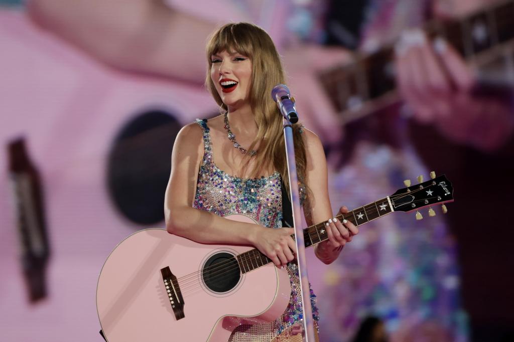 Taylor Swift holding a pink guitar during an Eras Tour concert